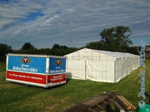 Das Zelt steht komplett, vorne sind noch Reste vom Zeltboden und der Getränkewagen ist von der Reithalle auch schon vor das Zelt gestellt worden.