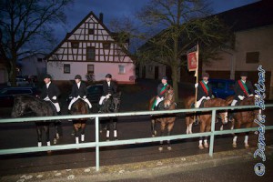 Auf der Straße vor dem Gasthaus haben sich die Reiter aufgestellt..