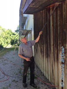 Hier spritzt Gebhard das Holz an der Halle ab...