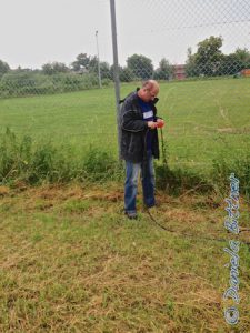 Helmut zieht gerade das Elektrokabel aus dem Gras entlang des Zaunes zum Sportplatz...