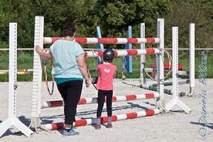 Hindernisstangen mal ganz anders... Mehrere Kuhglocken hängen an den Stangen und die Kinder sollen Hula-Hopp-Reifen von einem Ende zum anderen bringen, ohne dass eine Glocke läutet. Heißer Draht spezial... Birgit Boschatzke hat hier die Aufsicht übernommen...